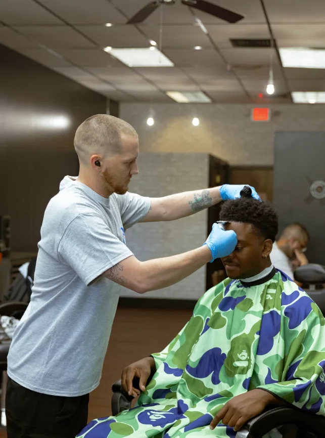 Jerm performing a haircut on a client in the shop