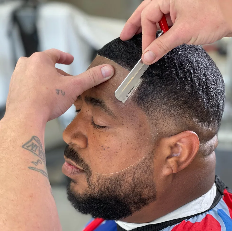 Jerm finishing a client's hairline with a brush