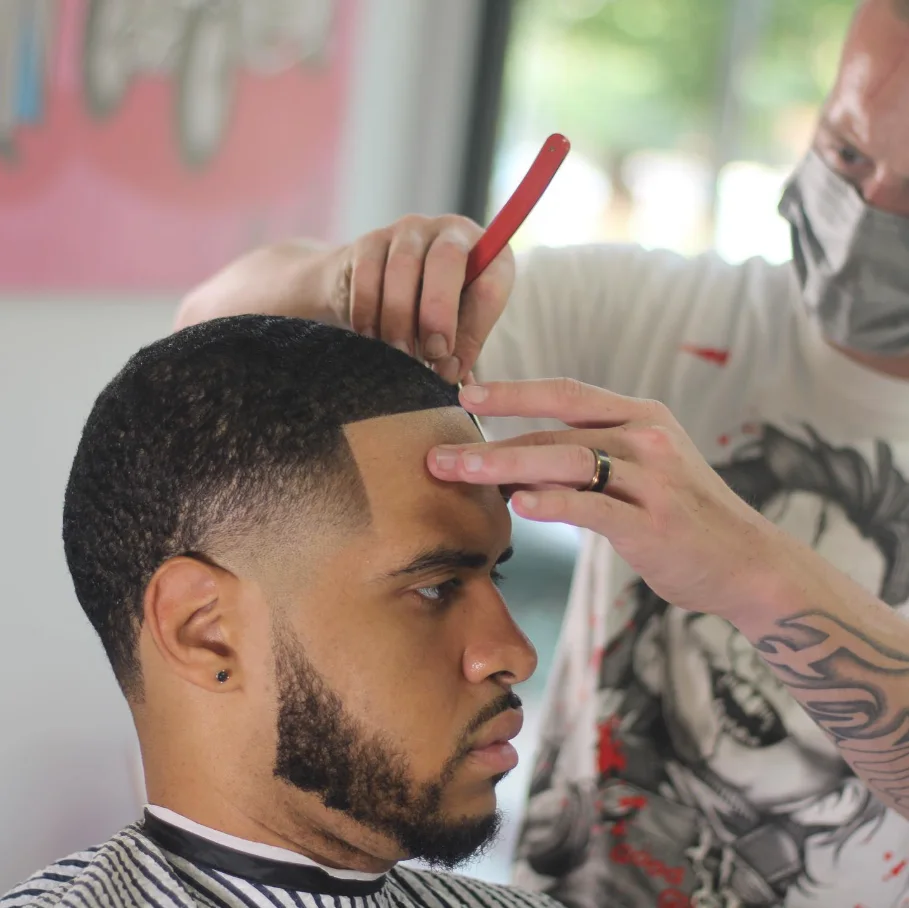 Jerm detailing a client's hairline with a comb