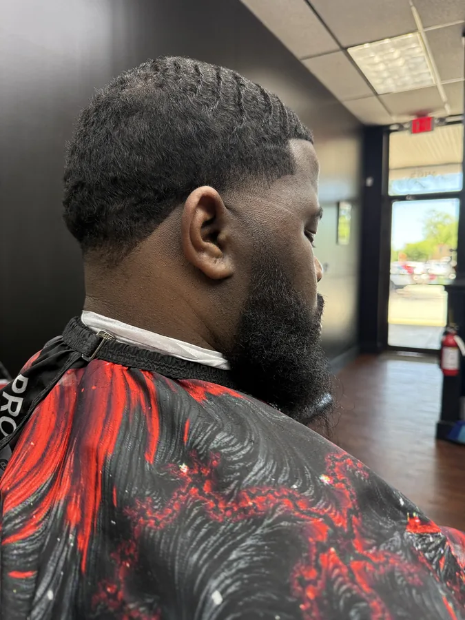 A finished fade in profile, the beard edged into a sharp line under the jaw