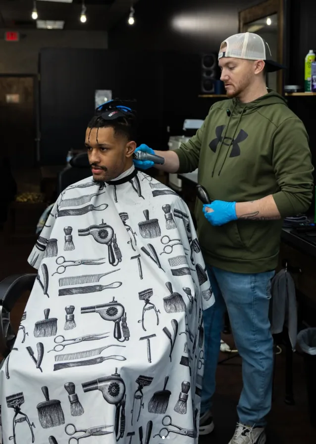 Jerm using clippers on a client's haircut in the shop